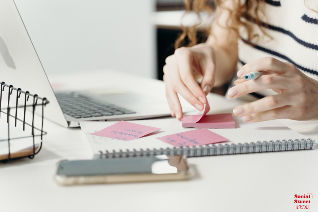 Sharing stories on social media: person writing notes on post-its while working at their desk on their social media strategy and storytelling content. 